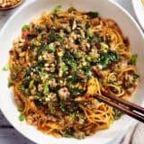 Overhead view of a bowl of dan dan noodles with chopsticks.