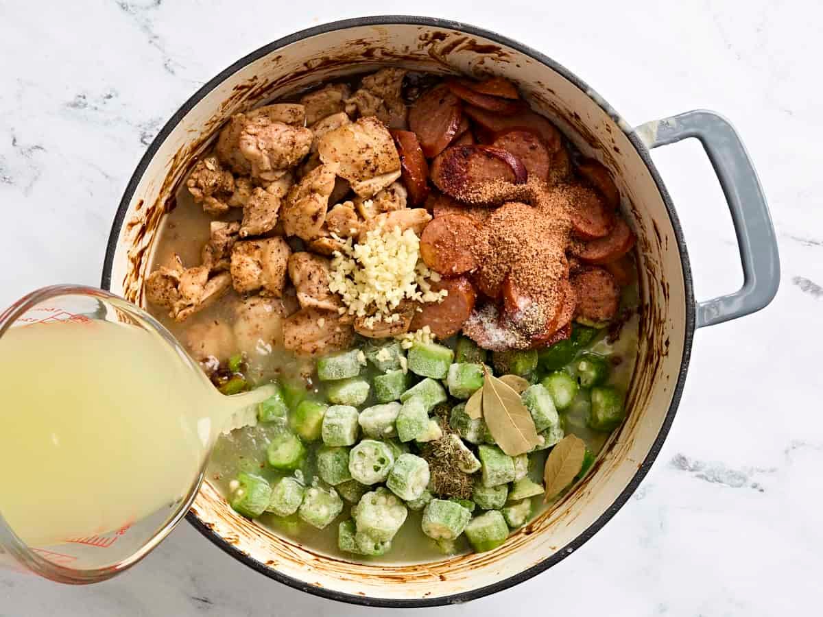Frozen okra, browned chicken and sausage, seasonings and broth in a pot.