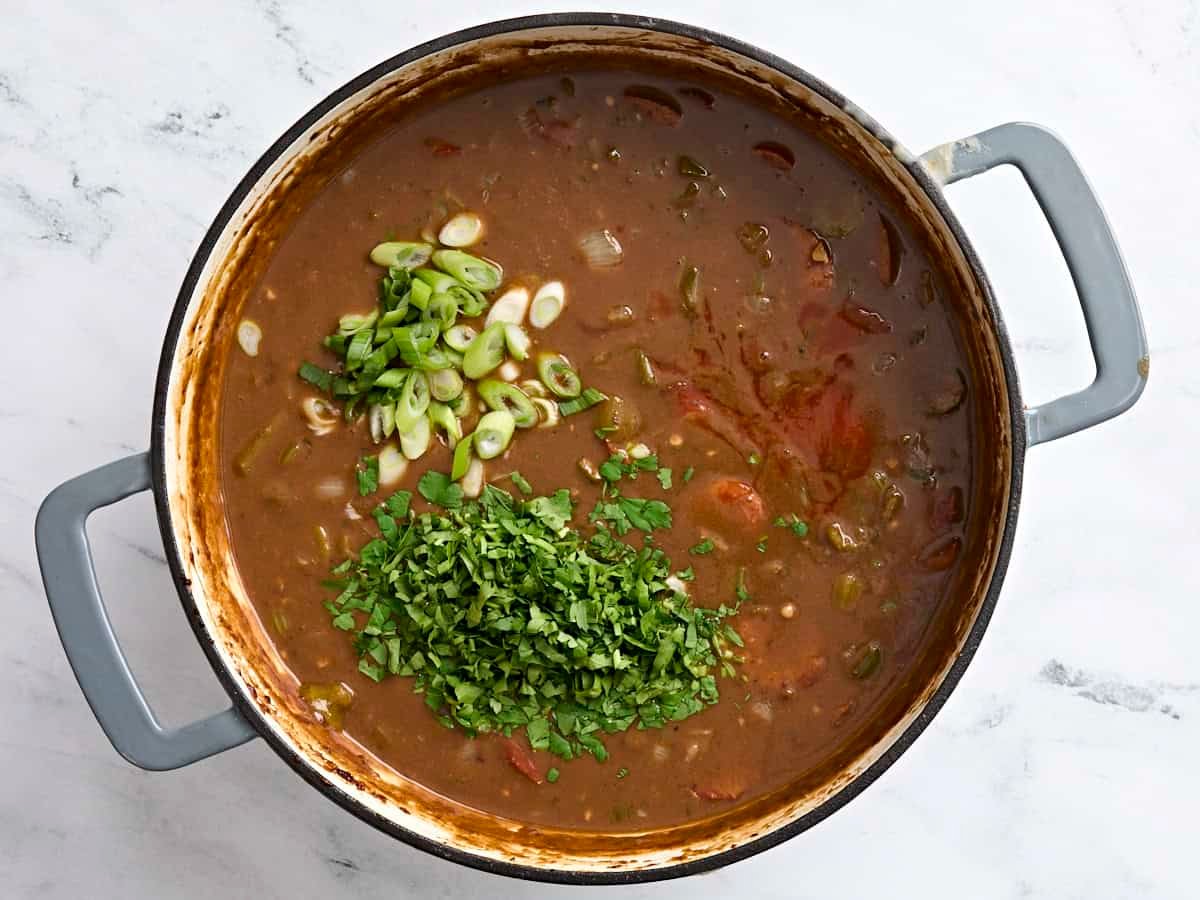 Green onions, parsley, and hot sauce in a pot of gumbo.