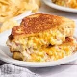 Tuna melt sandwich cut in half on a white plate.