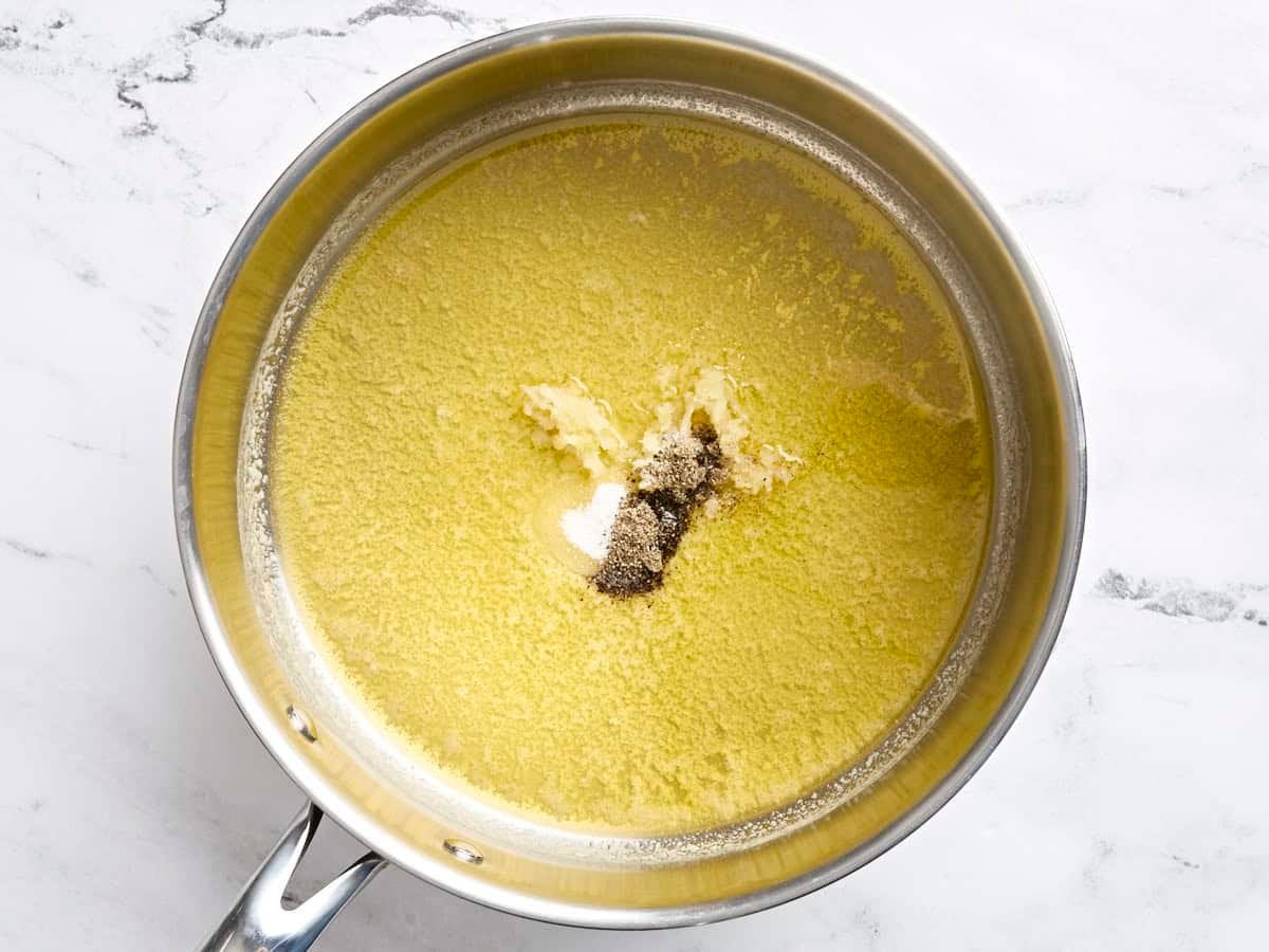 Melted butter in a skillet with salt, pepper, and minced garlic.