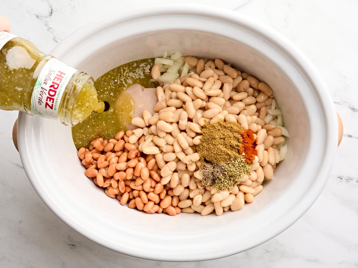 Canned beans, salsa verde, and seasonings added to crockpot.
