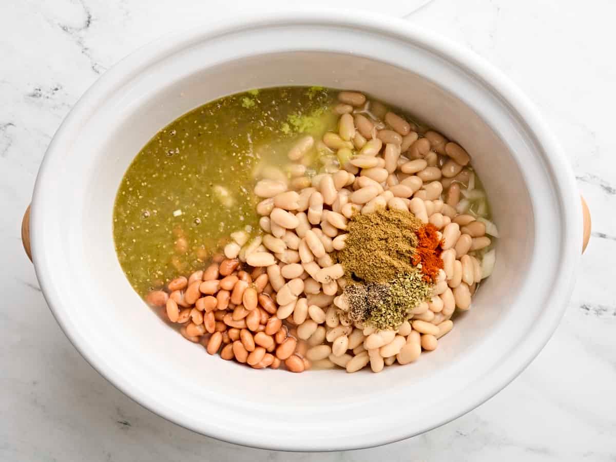 Stock added to a crockpot with the other ingredients for slow cooker white chicken chili.