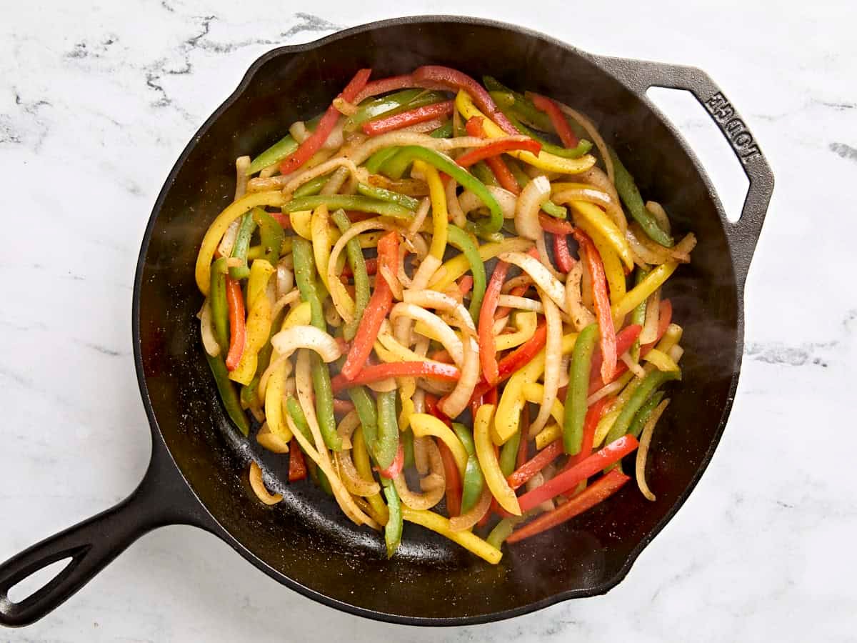Overhead view of cooked sliced peppers in a skillet.