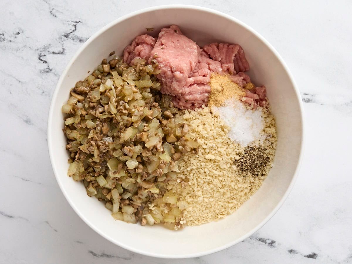 Cooked mushrooms and onions with panko bread crumbs and ground turkey in a bowl.