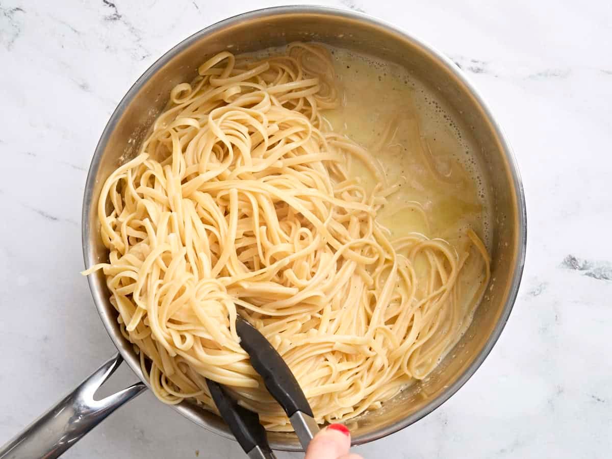 Fettuccine being tossed in a homemade alfredo sauce,