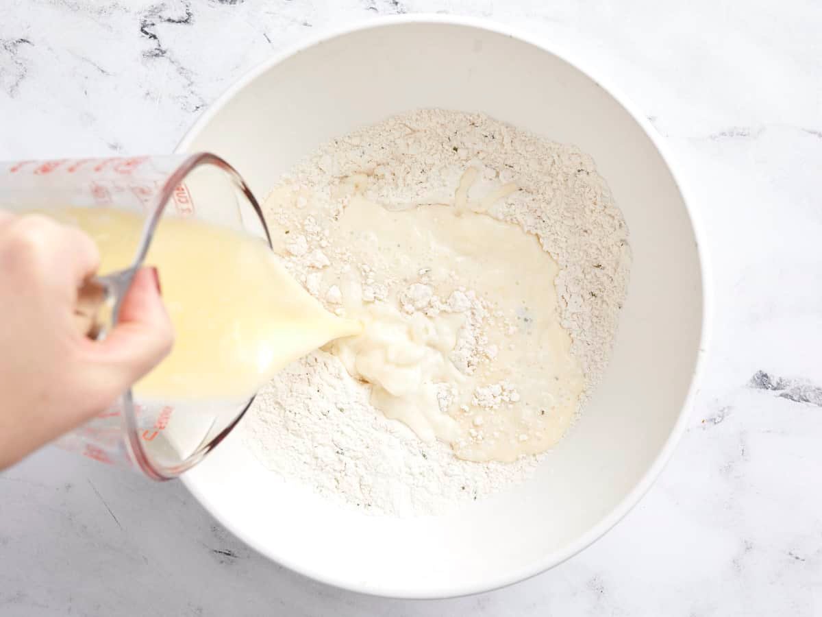 Wet ingredients being poured into the dry ingredients in a bowl.
