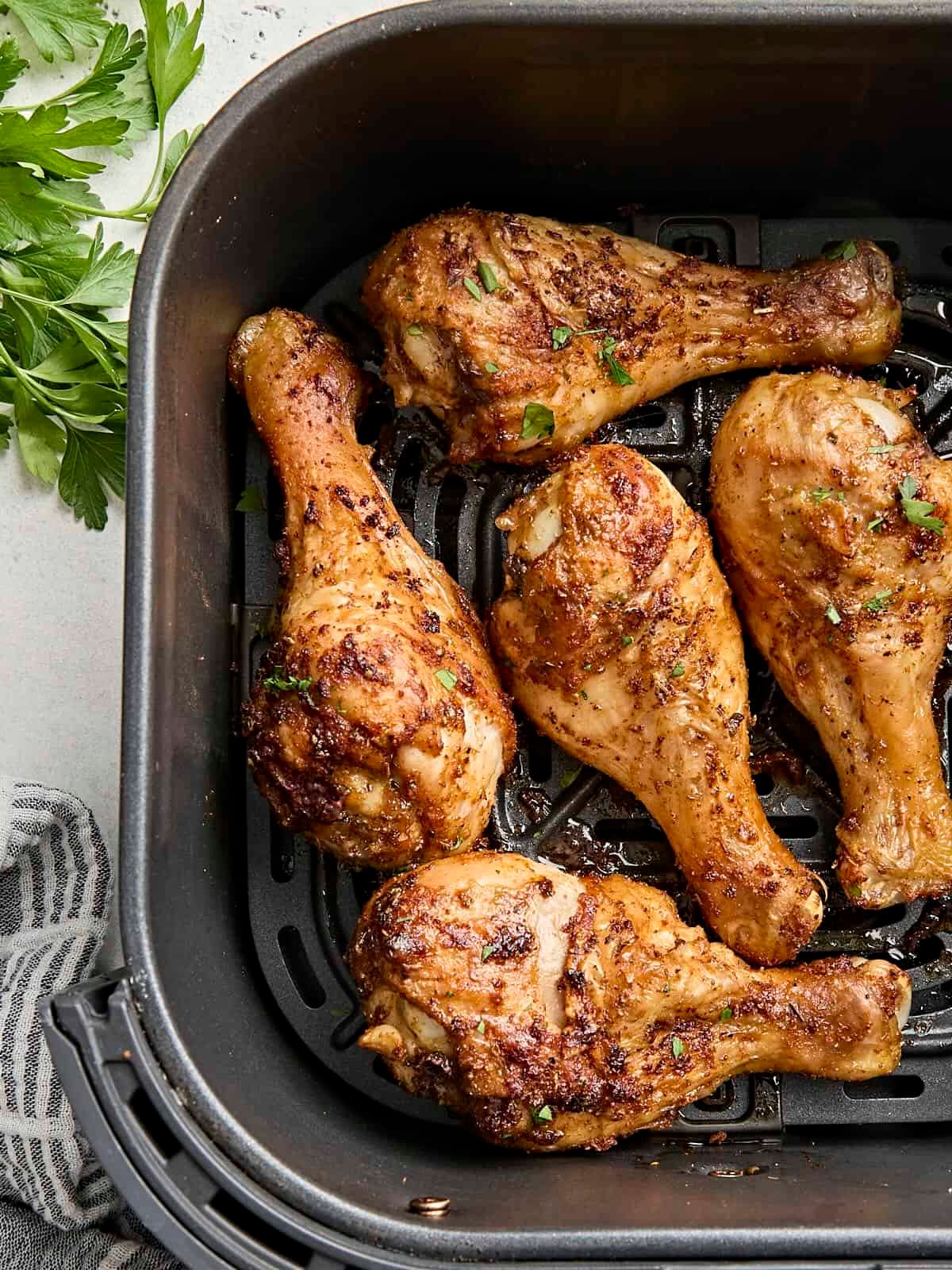 Overhead view of air fried chicken drumsticks in an air fryer basket.
