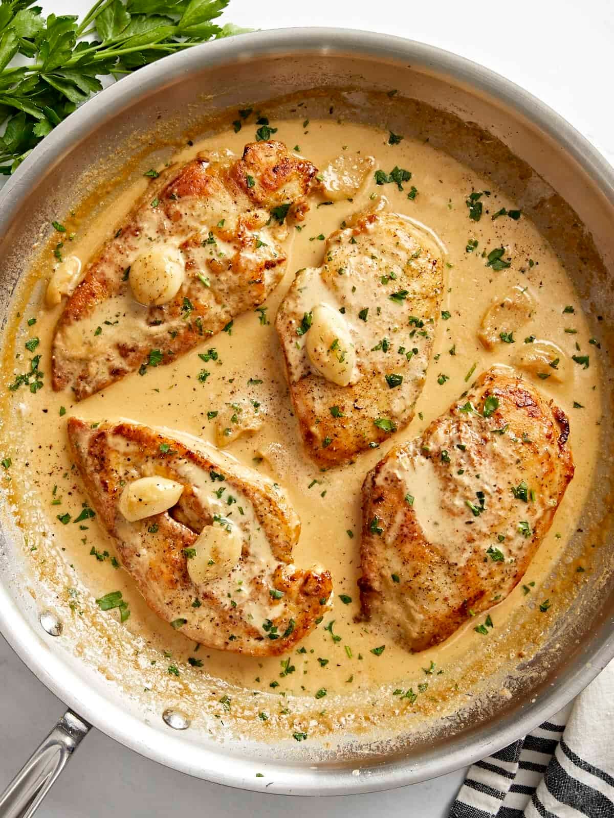Overhead view of Creamy Garlic Chicken in a skillet with parsley garnished on top.