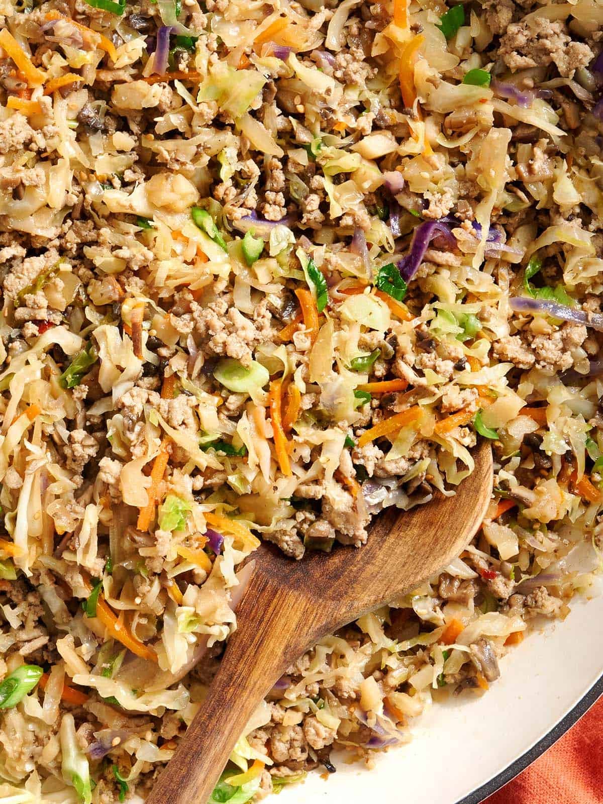 close up photo of egg roll in a bowl with a spoon scooping some out
