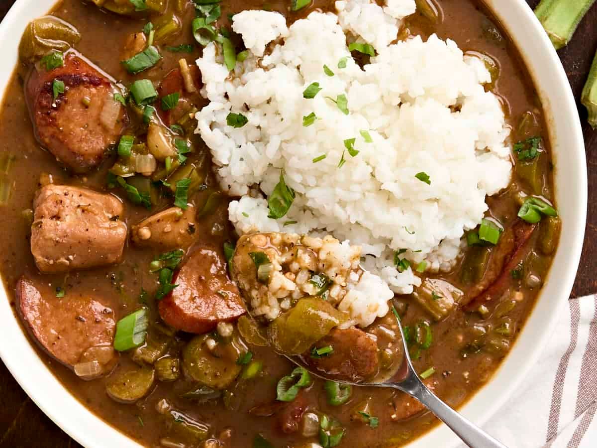 Overhead view of a bowl of gumbo and rice, with a spoon taking some.