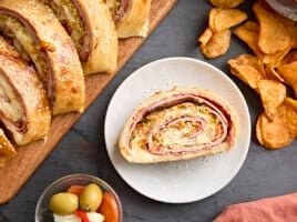 Plated Muffaletta roll-ups filled with layers of meats and cheese.