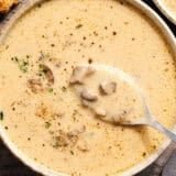 Overhead view of creamy mushroom soup in a bowl with a spoon.