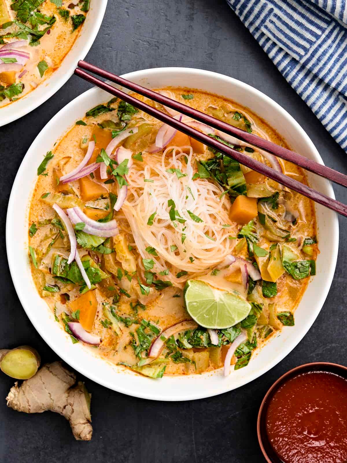 Overhead view of thai vegetable curry soup in a bowl with chopsticks.
