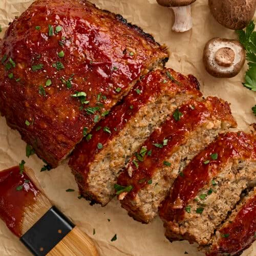 Overhead view of a homemade turkey mushroom meatloaf, with half of it cut into slices.