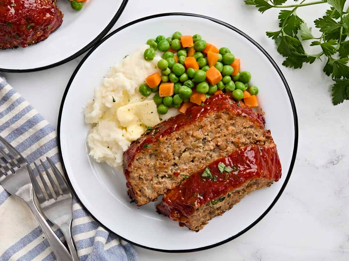 Overhead view of two turkey mushroom slices on a plate with mixed vegetables and mashed potatoes.