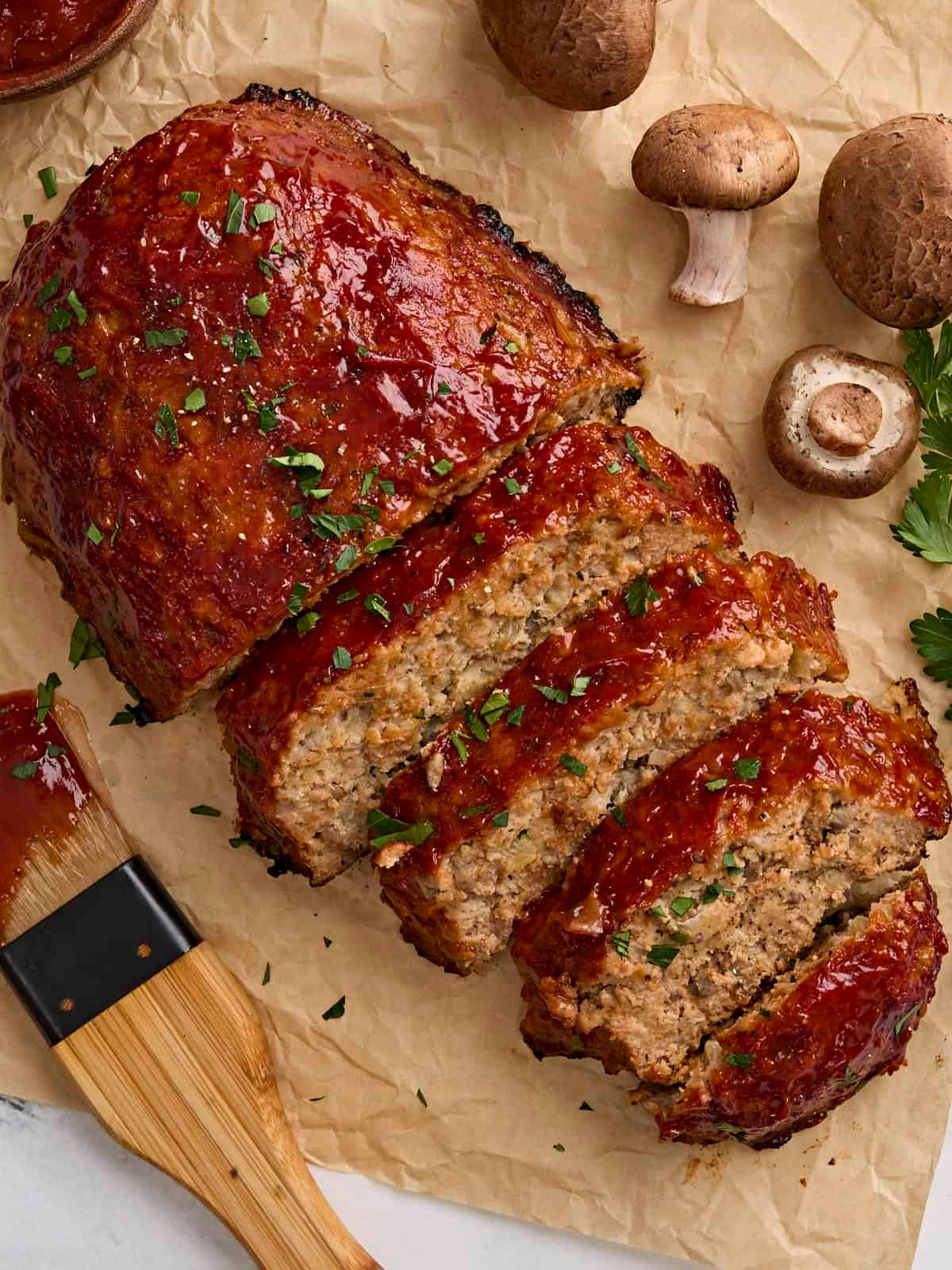 Overhead view of a homemade turkey mushroom meatloaf, with half of it cut into slices.