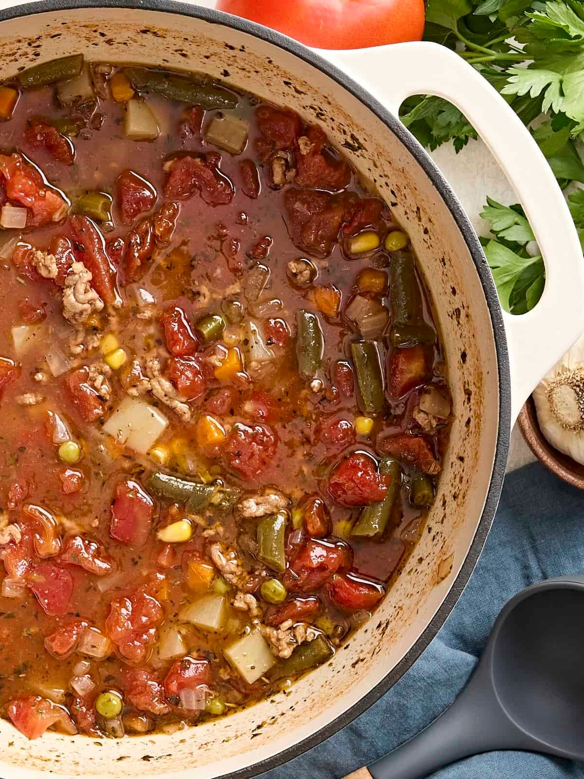 Overhead view of vegetable beef soup in a soup pot.